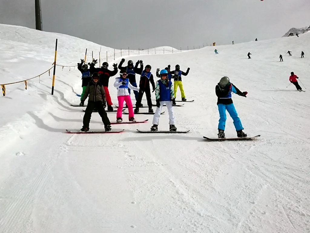 Snowboardgruppe reckt jubelnd die Arme.